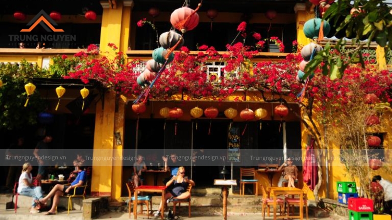 Góc check-in nổi bật tại một quán cafe với bức tường vàng, giàn hoa giấy