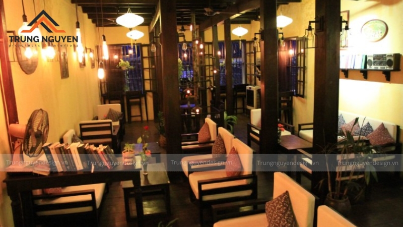 Một góc quán cafe mộc vào buổi tối, nổi bật với hệ thống đèn vàng ấm áp